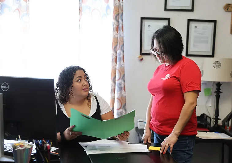 A CNMC caseworker reviewing immigration paperwork with a client